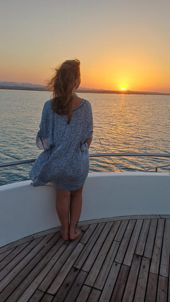 Laëtitia Campi de dos face au coucher du soleil, sur le pont d'un bateau en mer Rouge