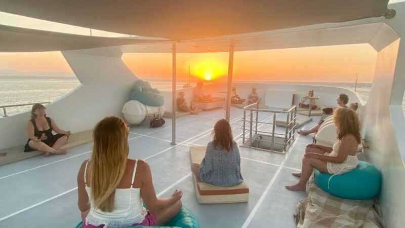 Méditation en groupe au coucher du soleil sur le bateau